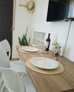 a wooden table with two plates and a bottle of wine at Monoambiente luminoso con Jacuzzi Relax y estilo in Córdoba