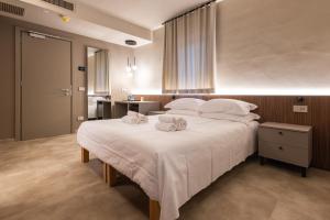 ein Schlafzimmer mit einem großen weißen Bett, auf dem Handtücher liegen in der Unterkunft Aima Boutique Rooms in Costa Volpino
