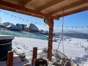 a porch with a swing in the snow at Cabana Popesti in Popeşti
