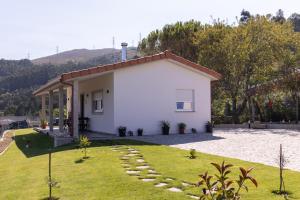 a small white house with a grass yard at Encosta da Cabreira in Vieira do Minho