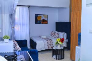 a bedroom with a bed and a blue couch at Naivera Membly Star Heights in Ruiru