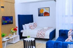 a bedroom with a bed and a blue chair at Naivera Membly Star Heights in Ruiru