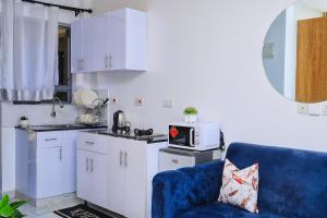 a kitchen with a blue couch and a microwave at Naivera Membly Star Heights in Ruiru