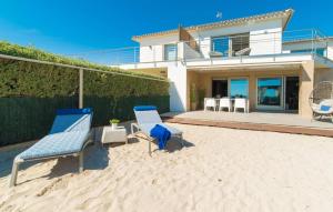 two blue chairs sitting in the sand in front of a house at Sa Platja in Playa de Muro +37 photos