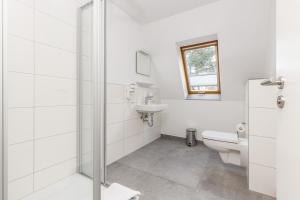 a white bathroom with a toilet and a sink at Feriendorf Strandgut in Altenkirchen
