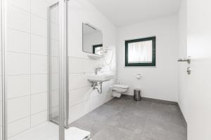 a white bathroom with a sink and a toilet at Feriendorf Strandgut in Altenkirchen
