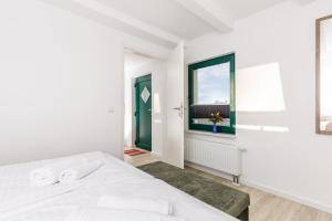 a white bedroom with a bed and a window at Feriendorf Strandgut in Altenkirchen