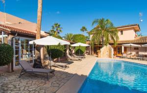 a swimming pool with chairs and umbrellas next to a house at Casa Romantica De Sa Coma in Sa Coma