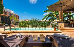ein Pool mit Tisch, Stühlen und Sonnenschirm in der Unterkunft Es Regaro in Capdepera