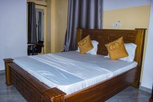 a bedroom with a wooden bed with yellow pillows at Hotel Mboloani in Lomé