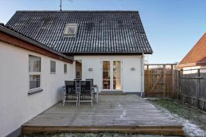 a small white house with a wooden porch with chairs at FY405-Millinge-Assensvej-422 in Faldsled +15 photos