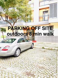 a silver car parked on a cobblestone street at Zenit little house or basic room in Olhão