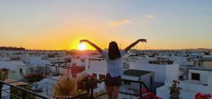 a woman standing on a balcony watching the sunset at Zenit little house or basic room in Olhão