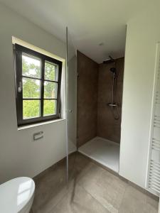 a bathroom with a shower and a toilet and a window at Ferienhaus Ovis Natur, Ruhe und Erholung in der Lüneburger Heide, Hunde willkommen in Winsen