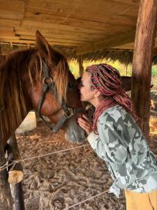 a woman is kissing a brown horse at Eco Lodges Chalets Tropicales Playa Macao in Punta Cana