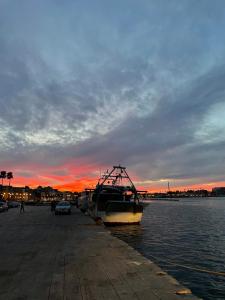 a boat is docked next to the water at sunset at Sonrisa Suites in Taranto