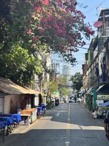 eine Stadtstraße mit einem Baum mit rosa Blüten in der Unterkunft Walk2BTS, KingBed, FastWiFi, FreeLaundry, Netflix in Klong Toi