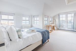 a white bedroom with a large bed and windows at The Tide House in St Ives