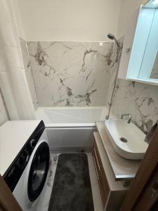 a bathroom with a washing machine and a sink at Tildy Apartman Pécs in Pécs