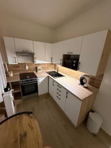 a kitchen with white cabinets and a stove top oven at Tildy Apartman Pécs in Pécs