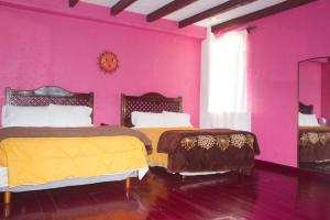 two beds in a room with pink walls at HOTEL & RESTAURANTE Los solaches in Zitácuaro