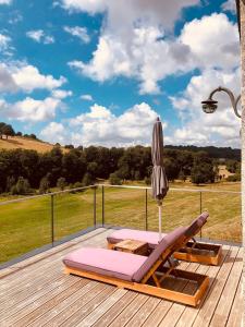 an umbrella and lounge chairs on a deck with a view at La Grange de Timon in Laguiole