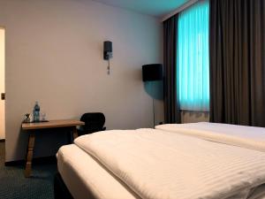 a hotel room with two beds and a table and a window at Gasthof Hotel Bräustübl und Haus Boutique in Selb