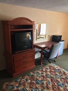 a hotel room with a desk and a tv and a bed at Home Town Inn in Flint