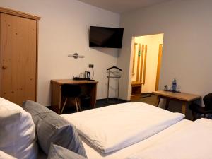 a bedroom with two beds and a desk and a television at Gasthof Hotel Bräustübl und Haus Boutique in Selb
