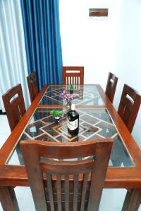 a glass table with a bottle of wine on it at Induwara Beach Stay Thalalla in Delgalla