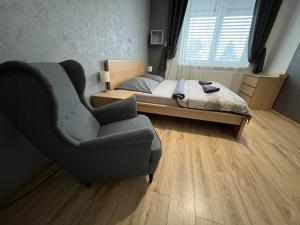 a small bedroom with a bed and a chair at APARTMENTS TRENČÍN -Free Parking- in Trenčín
