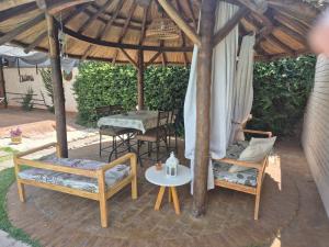 a patio with two chairs and a table and an umbrella at Dharma in Ciudad Lujan de Cuyo