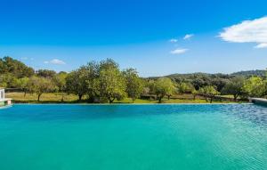 a large pool of blue water with trees in the background at S'oratge in Artá