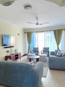 a living room with blue couches and a tv at MoDi's Seaside Nest in Mombasa