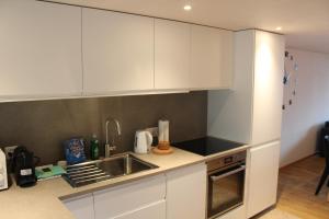 a kitchen with white cabinets and a sink at Apartment Büel in Krattigen in Krattigen +14 photos