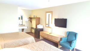 a hotel room with a bed and a chair and a tv at Oakdale Motel in Owatonna