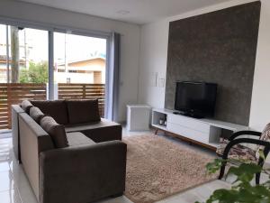 a living room with a couch and a flat screen tv at Casa com Piscina em Xangri-Lá RS in Xangri-lá
