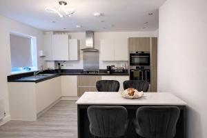 a kitchen with white cabinets and a table with chairs at Ebbsfleet Luxe in Swanscombe +6 photos
