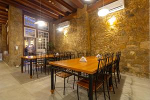 a restaurant with wooden tables and chairs and a stone wall at Pousada Aconchego in Paraty