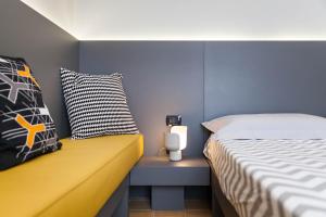 ein Schlafzimmer mit einem Bett und einer gelben Bank daneben in der Unterkunft B&B Portorosso in Monopoli