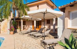 a patio with chairs and umbrellas next to a house at Casa Romantica De Sa Coma in Sa Coma