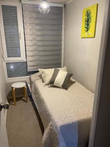 a small bed in a room with a window at Departamento outlet Puerto Montt con estacionamiento in Puerto Montt