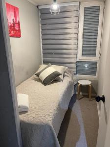 a small bed in a room with a window at Departamento outlet Puerto Montt con estacionamiento in Puerto Montt