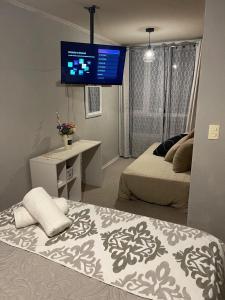 a bedroom with two beds and a tv on the wall at Departamento outlet Puerto Montt con estacionamiento in Puerto Montt