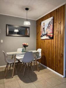 a dining room with a table and white chairs at Departamento outlet Puerto Montt con estacionamiento in Puerto Montt