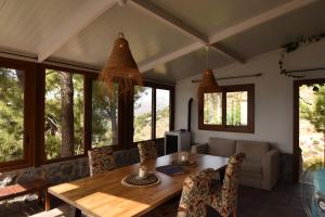a dining room with a table and chairs and windows at Finca La Sierra with private Pool in Cómpeta