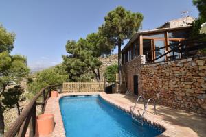 a house with a swimming pool next to a stone wall at Finca La Sierra with private Pool in Cómpeta