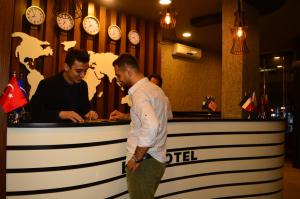 two men standing in front of a bar with clocks at Bern Hotel in Istanbul