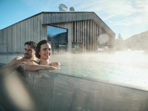two men are sitting in a hot tub at Hotel Kristall - Adults only in Leutasch