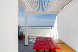 a red bench in a room with a view of the ocean at Buendía Corralejo Nohotel in Corralejo